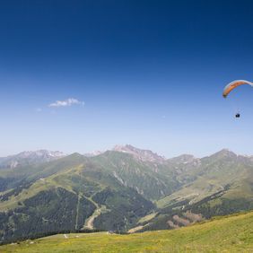 Paragleiter beim Fliegen im Sommer vor dem Panorama des Zilertaler Alpenhauptkamms